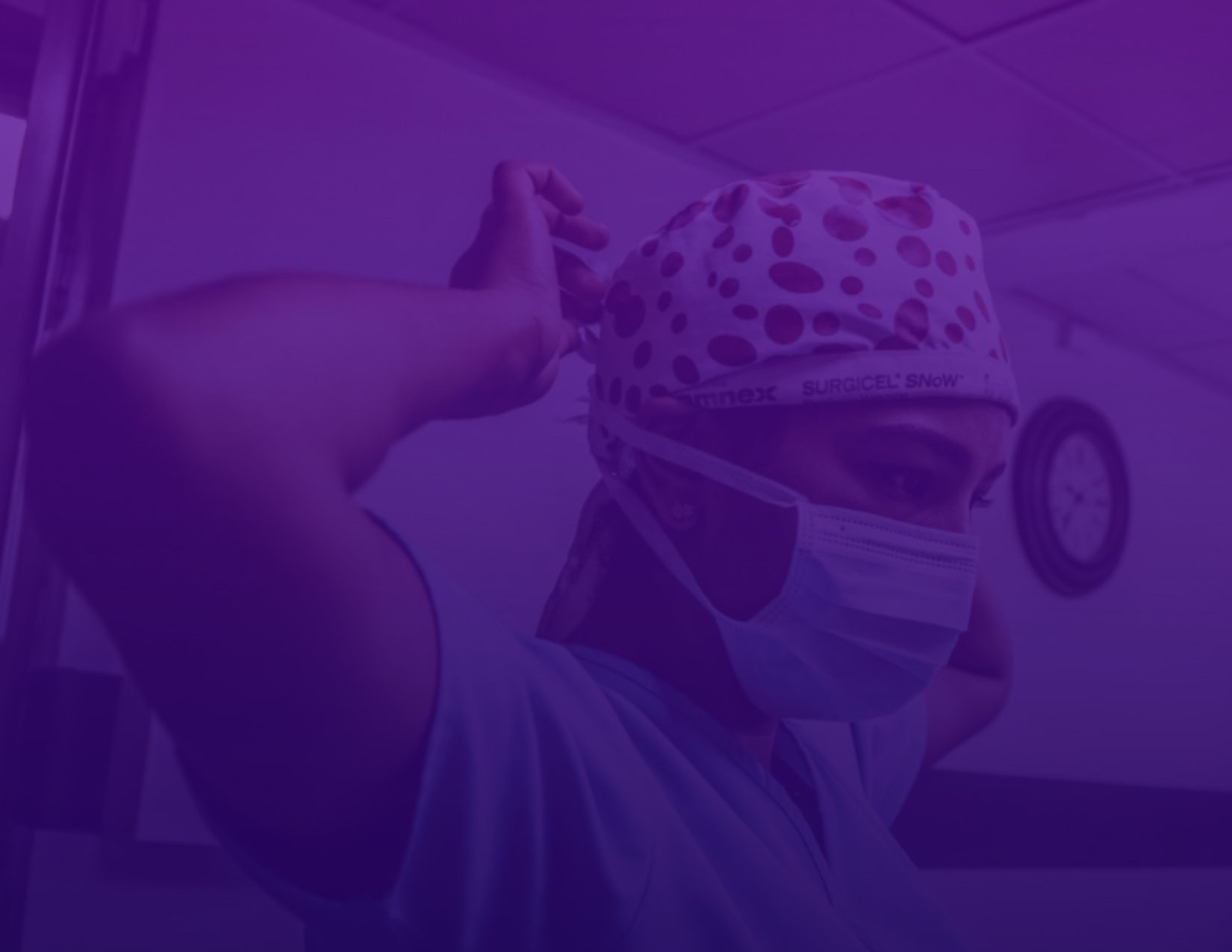 A female surgeon wearing a surgical mask and hat, ready to perform a medical procedure.